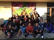 Students sitting in front of a banner outside in the late afternoon